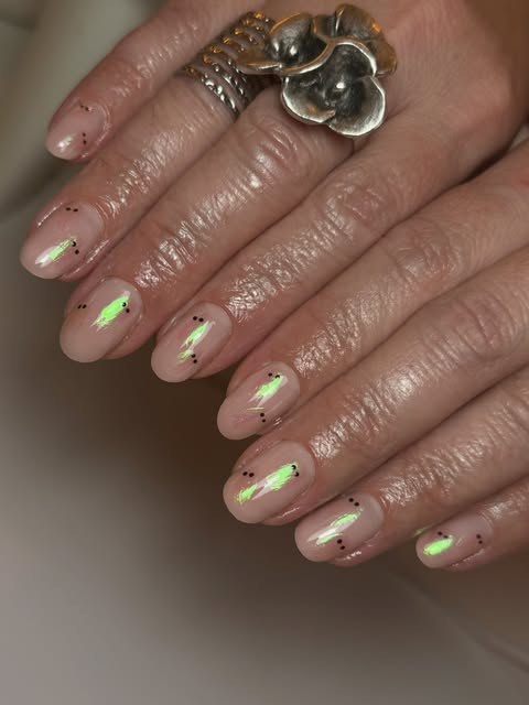 Sheer nude short nails with lime-green chrome lightning streaks and tiny black dots