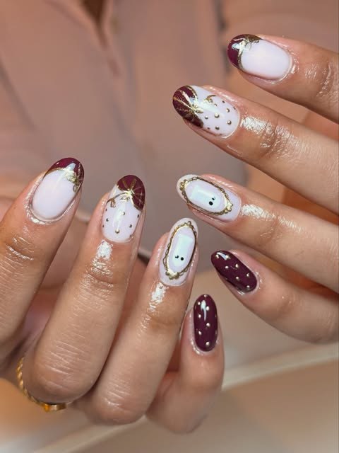 Milky white and deep burgundy almond nails with gold line work and gold dots
